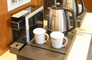 two cups on a counter with a coffee maker at Hotel Skypark Central Seoul Pangyo in Seongnam