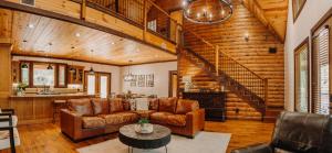 a living room with leather furniture and a staircase at Heated Pool, 7 Bedroom Cabin, 6,000 Square Feet, Arcade! in Broken Bow