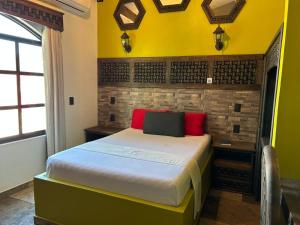a bedroom with a bed with yellow walls and red pillows at Hotel Villa's Camargo in Ixmiquilpan
