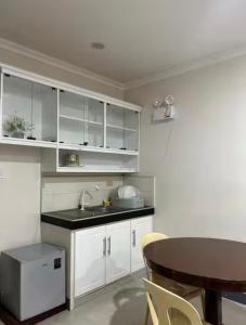 a kitchen with white cabinets and a sink and a table at Ashelma resort in Dauis