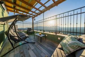 a balcony with a couch and a chair on a deck at Tzfat Regal - צפת ריגל in Safed