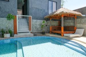 a swimming pool with a gazebo and a house at Urbanview Golden Barbie near Jawa Timur Park 2 in Tlekung