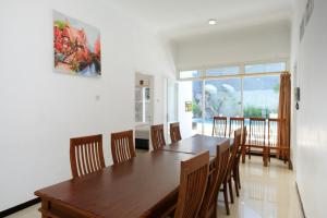 a dining room with a wooden table and chairs at Urbanview Golden Barbie near Jawa Timur Park 2 in Tlekung