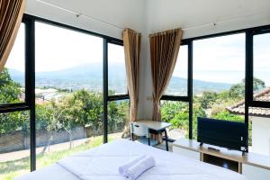 a bedroom with a bed and large windows at Urbanview Golden Barbie near Jawa Timur Park 2 in Tlekung