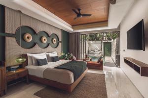 a bedroom with a large bed and a television at Monolocale Resort & Spa Seminyak by Ini Vie Hospitality in Seminyak