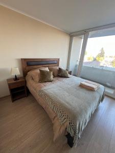 a bedroom with a large bed with a large window at Genesis in Chillán