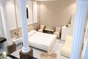 a bedroom with a bed and two chairs and columns at Phước Hưng 1 Hotel in Vĩnh Long +49 photos