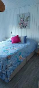 a bed with a blue comforter and a pink pillow at Cabaña Chango in Coquimbo