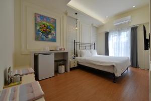 a bedroom with a bed and a painting on the wall at Station B&B in Tainan