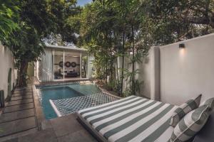 a swimming pool with a bed next to a house at Monolocale Resort & Spa Seminyak by Ini Vie Hospitality in Seminyak