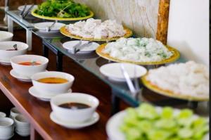 a buffet with plates of food and bowls of soup at Xavia Hotel Quy Nhơn in Quy Nhon