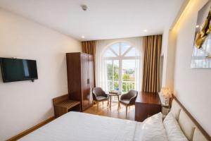 a hotel room with a bed and a desk and a window at Xavia Hotel Quy Nhơn in Quy Nhon