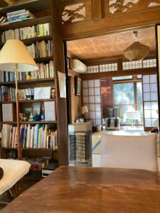 a room with bookshelves and a table with a lamp at ＯＫＵＮＯ ＩＥ in Oshima