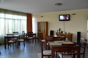 a dining room with tables and chairs and a tv on the wall at Pensiunea Flora in Cicir