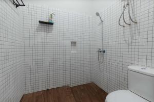 a white tiled bathroom with a toilet and a shower at Imah Budi Luhur in Bandung +12 photos