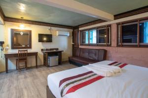 a bedroom with a bed and a couch and a television at P1 House Phitsanulok in Phitsanulok
