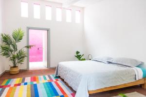 a white bedroom with a bed and a colorful rug at Shanti Home in Tepoztlán