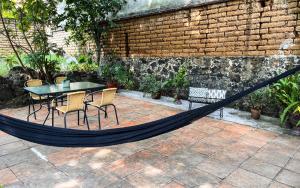 a hammock on a patio with a table and chairs at Shanti Home in Tepoztlán