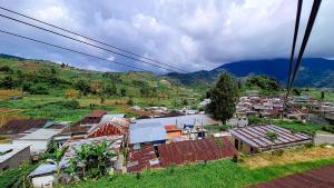 a village with houses and mountains in the background at Zaada Villa Dieng Syariah By Travelink in Kejajar +8 photos