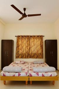 a bedroom with two beds and a ceiling fan at Home Nest in Anand