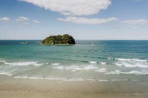 a small island in the ocean next to a beach at Sun filled & Spacious with Ocean Views & beach in Mount Maunganui