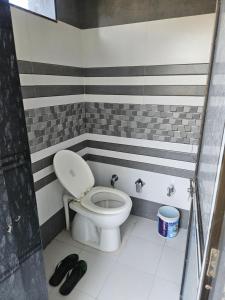 a bathroom with a toilet with stripes on the walls at Home Nest in Anand