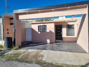 ein rosafarbenes Haus mit einer Auffahrt davor in der Unterkunft Libano in Manuel F. Martínez