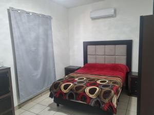 ein Schlafzimmer mit einem Bett mit einer roten Decke in der Unterkunft Libano in Manuel F. Martínez