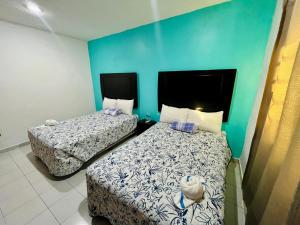 two beds in a room with a blue wall at Aibilins in Veracruz