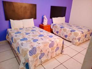 a bedroom with two beds and a table with a bedspread at Aibilins in Veracruz