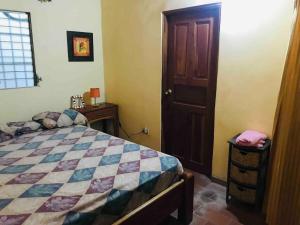 a bedroom with a bed and a wooden door at Casa estilo campestre in Chitré +6 photos
