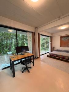 a bedroom with a desk with a computer and a bed at Lakehouse in the Old Rainforest in Ko Phangan