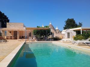 a swimming pool with blue water in front of a house at Trullo del Sol in Ceglie Messapica