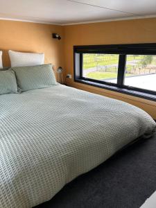 a bedroom with a bed and a large window at Gorgeous private tiny home in  Waipukurau