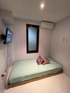 a small bed in a small room with a mirror at Sanur Backpacker Room Bali in Sanur