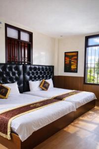 two beds in a bedroom with a black headboard at Window 2 Hotel in Kon Tum