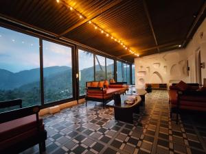 a living room with couches and tables and windows at Nomada in Mount Ābu