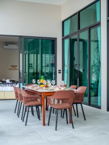 a dining room with a wooden table and chairs at Gam-Hom Poolvilla ชะอำ in Ban Hua Phrong