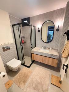 a bathroom with a sink and a toilet and a mirror at Marinaya 13 dakika tasarımlı daire in Mersin +17 photos