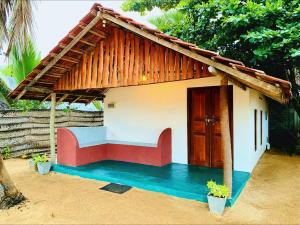 a small house with a thatched roof at Sunrich Beach Resort in Ilandaiyadi