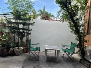 two chairs and a table in a courtyard with plants at Bacolod Transient Home in Bacolod