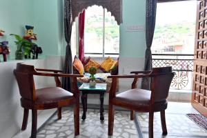 two chairs and a table in a room with a window at The Rajputana Heritage in Jodhpur