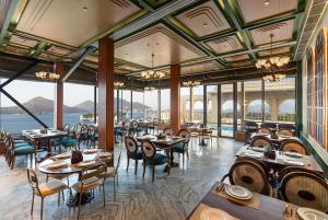 a dining room with tables and chairs and windows at Acacia Somgarh Udaipur in Udaipur