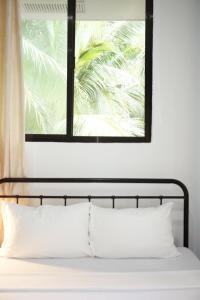 a bed with white pillows in front of a window at Mayas Guesthouse in Panglao Island