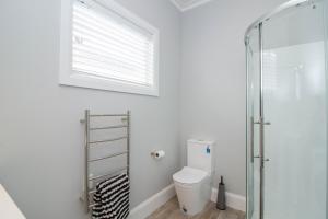 a bathroom with a toilet and a glass shower at Bolton Street Cottage in Lower Hutt +5 photos