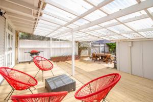 a patio with red chairs and a roof at Bolton Street Cottage in Lower Hutt