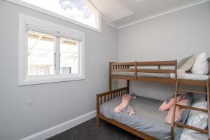 two children are laying on bunk beds in a room with a window at Bolton Street Cottage in Lower Hutt