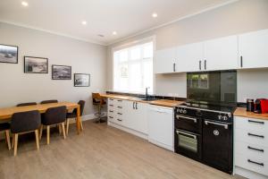 a kitchen with white cabinets and a wooden table at Bolton Street Cottage in Lower Hutt