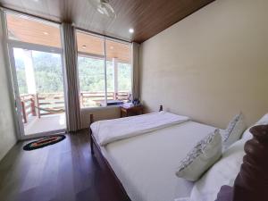 a bedroom with a bed and a large window at Phetdavanh Guesthouse in Ban Ngoy-Nua