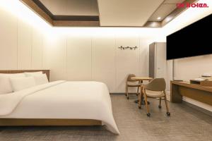 a bedroom with a bed and a desk and a tv at Jinju KAI Tourist Hotel in Jinju